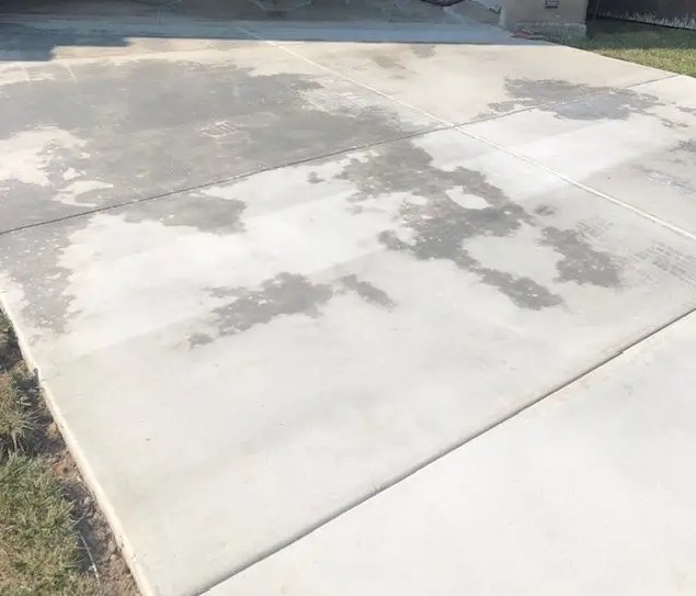 Untreated concrete driveway with water soaking in and staining in Northern Utah
